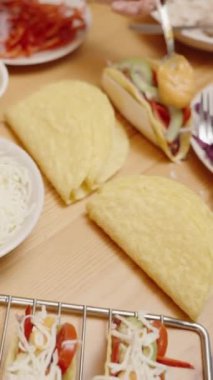 Dikey video. Peynir, Salsa ve Sebzeler de dahil olmak üzere içindekilerle birlikte toplanmaya hazır tacolar..