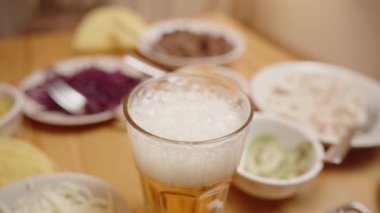 Bir bardak köpüklü bira Taze hazırlanmış taco ve kaselerin yanında bir masanın üzerinde duruyor..