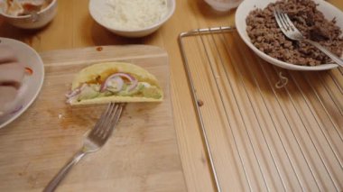 Bir Kişinin Eli Kırmızı Biber ve Soğanları Dilimlenmiş Taco Kabuğuna Koyuyor, Çeşitli Toplama ve Malzemeler Yakınlarda.