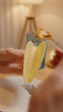 Dikey video. Taze malzemelerle ev yapımı taco yemeye hazırlanan bir kişi ahşap masa üzerindeki çeşitli malzemelerle çevrelenmiş..