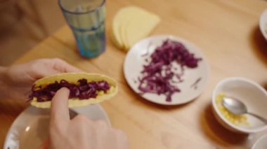 Bir Kişi İçi Mısır Dolu Taze ve Lezzetli Bir Tabak Yaratan Taco Kabuğuna Parçalanmış Kırmızı Lahana Ekliyor.