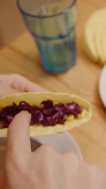 Dikey video. Bir Kişi İçi Mısır Dolu Taze ve Lezzetli Bir Tabak Yaratan Taco Kabuğuna Parçalanmış Kırmızı Lahana Ekliyor.