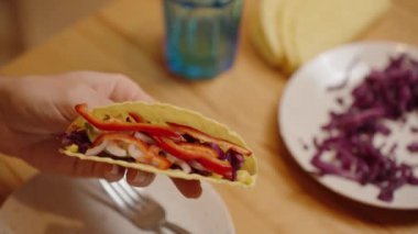 Bir Kişi Kırmızı lahana ve biberli takoya doğranmış peynir ekler. Lezzetli ve renkli bir yemek yapar..