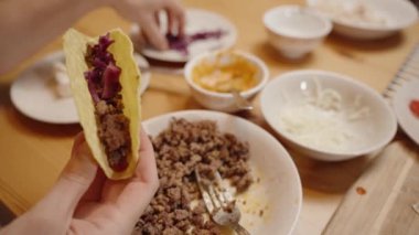 Bir Kişi Kıyılmış Kırmızı Lahanayı Köfte ile Doldurulmuş, Lezzetli Yemek Hazırlayan Bir Taco Kabuğuna Ekliyor.