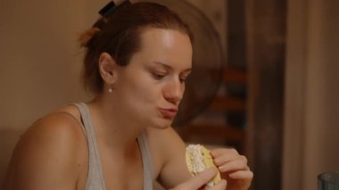 Bir kadın elinde taco tutarken mavi bardaktan bir yudum su alır ve ısırıklar arasında kendini tazeler..