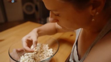 Bir kadın, bir kaseden patlamış mısırı alıp Sessiz Anın ve Atıştırmalığının tadını çıkarırken aşağıya bakar..