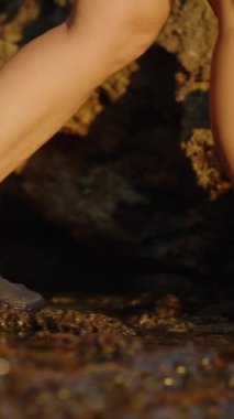 Dikey video. Koruyucu Su Ayakkabıları 'nda Rocky Arazisi' nde, Ayaklarını Keskin Taşlardan Korumak ve Sahilde Yürüme Deneyimini Geliştirmek İçin Dizayn Edilmiş Bir Kişi. Yavaş çekim.