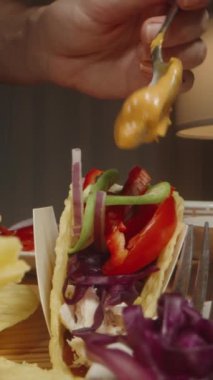 Dikey video. Taze sebzelerle dolu bir taco 'nun üzerine kaşık çiselemeli peynir sosu. Lezzetli bir tabak yaratıyor. Dolly kaydırıcı, kapat..