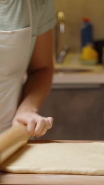 Dikey video. Unlu bir yüzeye ahşap bir raptiyeyle hamur işi yapmak, Üs 'ü pişirmeye hazırlamak.