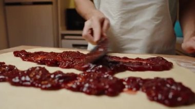 Siyah bir Spatula ile Hamur 'un üzerine kiraz reçeli serpiştirip, Lezzetli Bir Dolgu Oluşturmak.