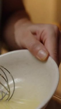 Dikey video. Büyük bir cam kaseye çırpılmış sıvıyı dökmek, Hamur Karışımının Hazırlanmasına Devam Etmek.