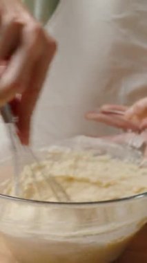 Dikey video. Cam bir kâsede Kalın bir Vurucu çırpmak, Bir Sonraki Fırın Adımına Hazırlanmak.