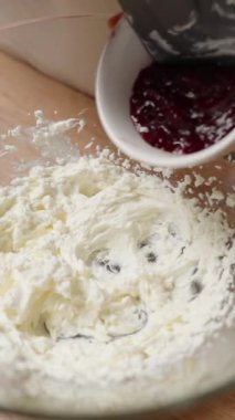 Dikey video. Büyük bir cam kasede vişne aromalı dondurmaya vişne reçeli ekliyorum. Yavaş çekim.