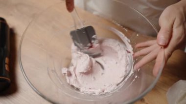 Vişne reçelini krema ile karıştırmak, Pembe vişne aromalı buzlanma yaratmak. Yavaş çekim.