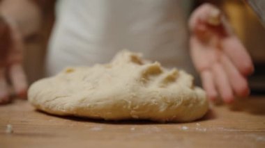 Tahta bir yüzeydeki elleri yassılaştıran Hamur, Hamuru pişirmek için şekillendirmeye hazırlanıyor, hatta dokuyu sağlamlaştırıyor. Yavaş çekim.