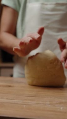 Dikey video. Tahta bir yüzeyde hamur hazırlayan kişi, Dough yassılaştırılmış ve daha ileri şekillendirme ya da pişirme adımlarına hazır. Yavaş çekim.