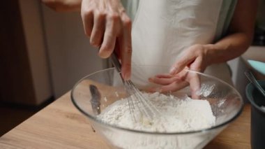 Erimiş unu cam kasede çırpılmış unla karıştıran kişi, tarif için malzemeleri birleştiren kişi, pişirme sürecine odaklan. Yavaş çekim.