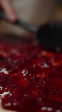 Dikey video. Black Spatula 'nın vişne reçeli serpiştirme sahnesine yakın plan, Eşitlik ve Üniforma Kapsamını Sağlama. Yavaş çekim.