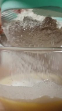 Dikey video. Un bir cam kaseye konur, ince bir toz oluşturur, pişirmeye hazırlık sürecini geliştirir. Yavaş çekim.