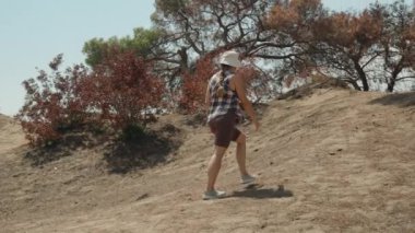 Kuru Ağaçlar ve Çorak Arazi ile çevrili Kuru, Günışığı Yolu 'nda Bir Kadın Tepeye Çıkıyor.