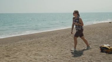 Bir kadın kumsalda yürüyor, sakin okyanusa bakıyor, Horizon onun önünde uzanıyor..