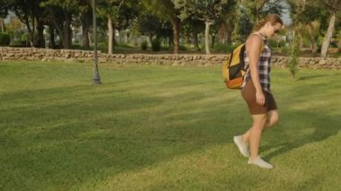 Sırt çantasıyla gezen bir kadın Grassy Parkı 'nda yürüyor. Doğaya dalmış ve günün sıcaklığında..