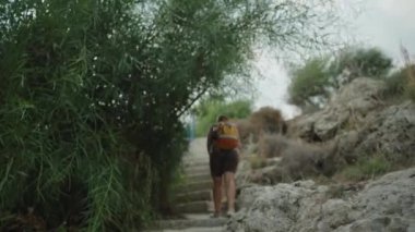 Rocky Hill 'e oyulmuş Dar Merdiveni tırmanan Bir Kadın. Uzun Yeşillik Yolu Üzerine Kemerler, Yükselirken Doğal bir Tepe Oluşturur.