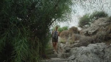Yeşilliklerle çevrili Taş Merdivenlerden Dikkatle İnen Bir Kadın. Dar Yol 'da Dar Yol' da ilerlerken Nazikçe Dalları Uzağa itiyor.