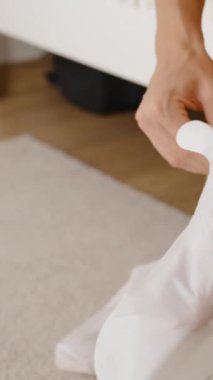 Dikey video. Bir kadın, etkin bir ayak soyma tedavisi için beyaz çorapları ayaklarının üzerine geçirir..