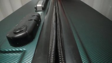 Bir el fermuarı çekerek bavula kapatır ve şifreyi kilitlemeden önce içindekileri emniyete alır..