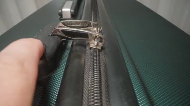 Bir el, valizin kilidinden çıkardığı fermuarı açar. Güvenli bir yolculuktan hemen sonra açılır açılmaz işaretler..