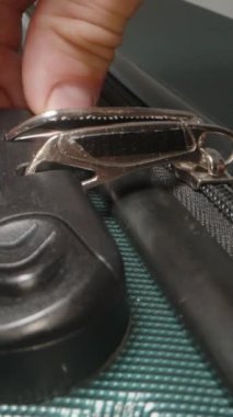 Dikey video. Bir El kilidin üzerindeki doğru kombinasyonu dikkatlice seçer, fermuarı açıp valizi açmaya hazırlanır.