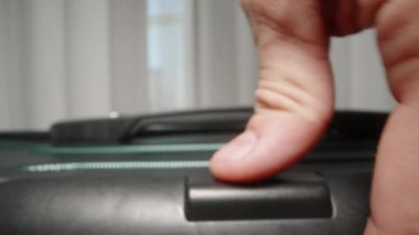 Bir El, valizin sapını sıkıca kavrar ve yolculuğa çıkmaya hazırdır. Güvenli bir şekilde kilitlenmiş valiz de yolculuk için hazırdır..