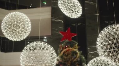 Noel ağacının tepesini çevreleyen parlak ışık küreleri çarpıcı bir görüntü oluşturuyor..