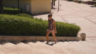 Lush Green Hedges 'in yanında bir taş merdivene tırmanan kadının adımları kaldırıma gölge düşürüyor..