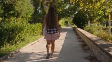 Sunny Day 'de Çevresi Yeşilliklerle çevrili Yapraklarla çevrili Bir Yolda Yürüyen Kadın İleriyi Gösteriyor.