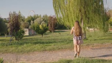 Parkta Ağlayan Ağlayan Büyük Söğüt Ağacı 'na doğru yürür. Arka planda dönme dolap görünür..