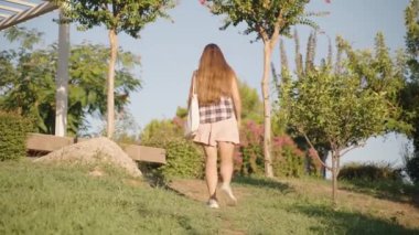Yürürken, kadın ağaçlar ve çalılarla çevrili Serene Park ayarı, Saçları özgürce akıyor.