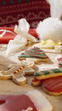 Dikey video. Tahta bir kurulda Zencefilli Çörek Adamlar, Eldivenler ve Şeker Çubukları da dahil olmak üzere çeşitli Noel temalı kurabiyeler. Kaydırıcı, kapat.