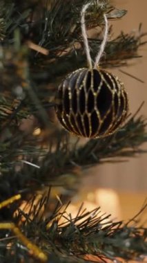 Dikey video. Kırmızı Şenlikli Süveter Giyen Bir Kadının Yakın Çekimi Bir Evdeki Altın Parlatıcı Tutkalla Bir Kağıt Noel Süslemesine Son Detayları Ekliyor.