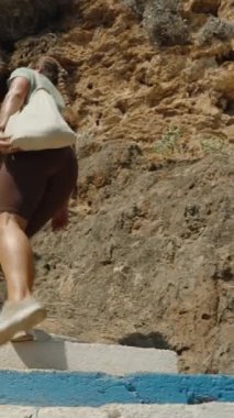 Dikey video. Aşağıdan Bakış, Beton Merdivenlere tırmanan Kadın, Rocky Hillside 'ı geçen, Parlak Gün Işığında Mavi Tırabzanı kavraan Kadın.