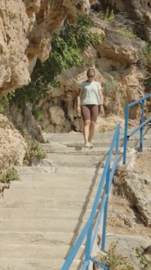 Dikey video. Rocky Cliffs ve Blue Railings tarafından çevrelenmiş Lush Greenery, Ocean in the Distance.