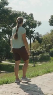 Dikey video. Çevresi yeşillik, eskrim ve arka planda okyanusla çevrili, Gökyüzü açık güneşli bir gün..