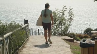 Piknik Bölgesi 'ne Yürüyen Kadın, Güneş Işığı Okyanusuna Bakan Yeşil ve Eskrim, Parlak ve Huzurlu Atmosfer.
