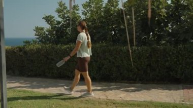 Çöp Kutusunda Çöpü Atan Kadın, Bir Taş Yolu 'nda Duran Okyanus ve Fırça Arkaplanda, Parlak ve Açık Gün.