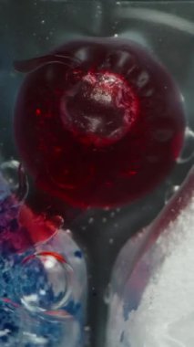 Dikey video. Bulaşık makinesinin yakın plan görüntüsü Eritme, Kırmızı ve Mavi Deterjanlar Karıştırma, Girdap ve Kabarcıklar Yaratma.