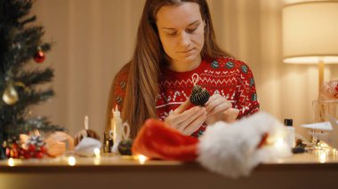 Odaklanmış Kadın Dikkatlice İnceleme Tamamlanmış Süsleme, Hazırlık Malzemeleri ile çevrili.