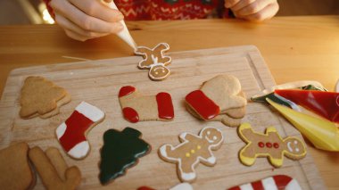 Beyaz Buz Adam Kurabiyesine Beyaz Buz Ekliyor, Tahta Tahtadaki Çeşitli Kurabiyelerle çevrili.