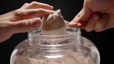 Protein tozunu parmaklarıyla yumuşatan bir sporcunun yakın çekimi, ideal performans için tam servis büyüklüğüne ulaşır. Yavaş çekim.