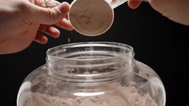 Sporcunun elleri, karıştırmak için doğru bir kısmı sağlama almak için bir top Protein tozu tutuyor. Yavaş çekim.
